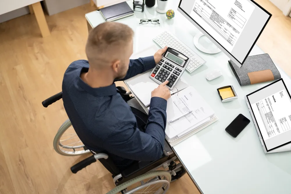 "NDIS provider reviewing participant invoices and financial records on a laptop"